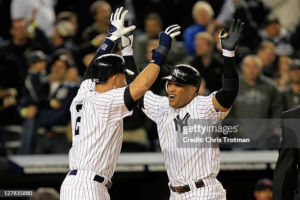 Robinson Cano of the New York Yankees is congratulated by Derek Jeter after hitting a grand slam home run in the sixth inning of Game One of the...