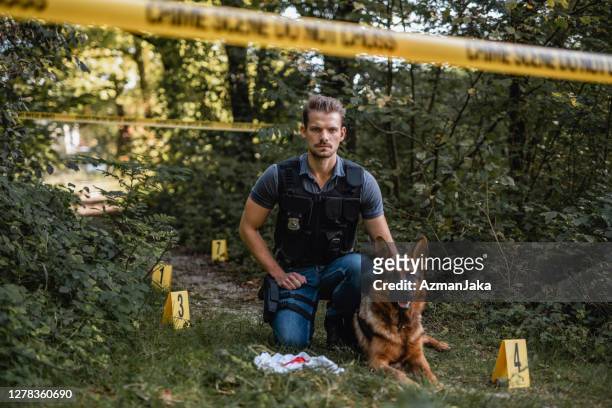 agente di polizia k9 e cane addestrato sulla scena del crimine boschivo - cane poliziotto foto e immagini stock