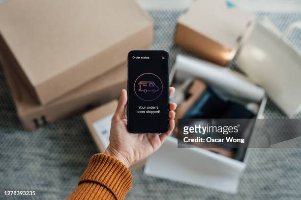 your order has been shipped - close up shot of hand holding smartphone with online shopping box stack at the background - hitech moda stock-fotos und bilder