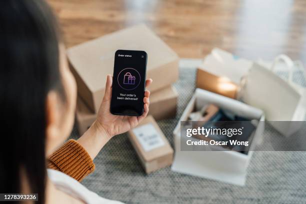 your order has been delivered - close up shot of hand holding smartphone with online shopping box stack at the background - christmas celebrations in china stock pictures, royalty-free photos & images