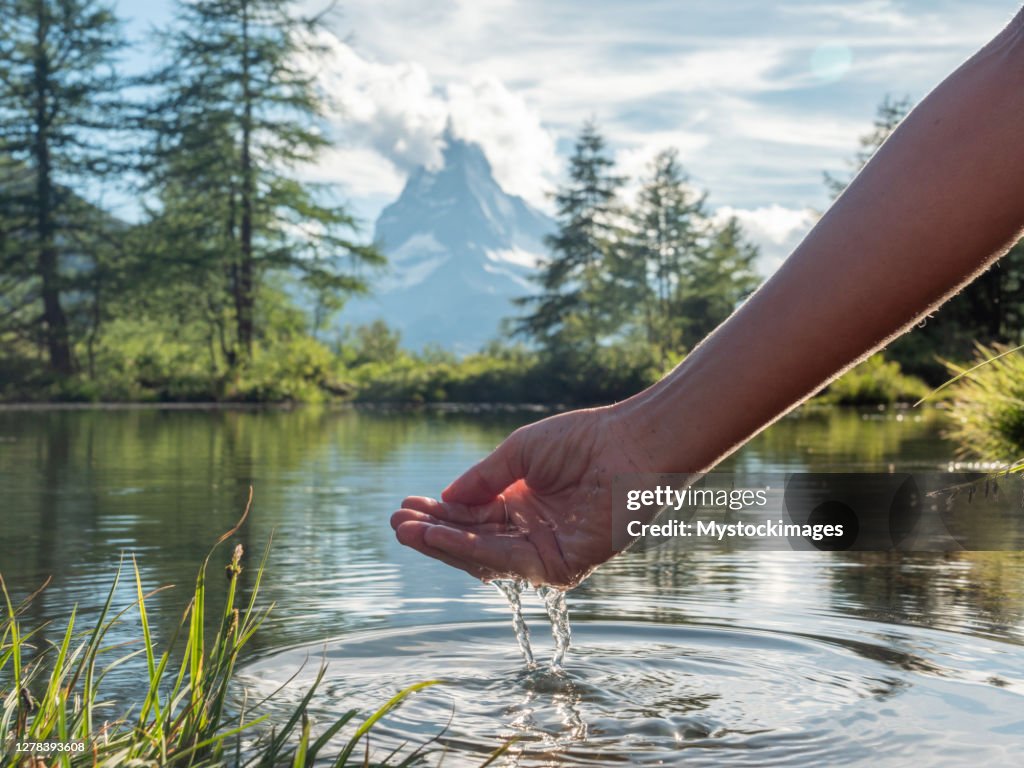 Hände, die Wasser aus dem Alpensee schöpfen