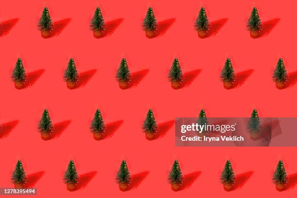 holiday pattern made of green christmas trees on red background. - row of christmas trees stock pictures, royalty-free photos & images