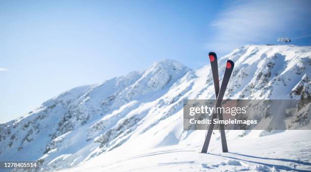 skis crossed and stuck in the snow in front of the top of the ski resort. - pole foto e immagini stock