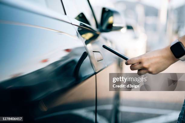 close up of young asian woman using mobile app device on smartphone to unlock the doors of her car in a car park - opening car door stock pictures, royalty-free photos & images