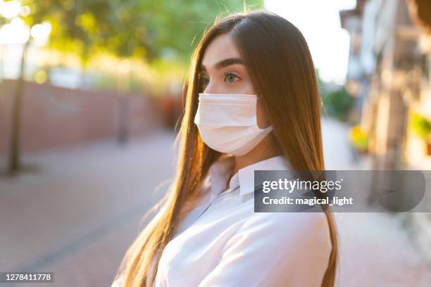 woman wearing face mask because of air pollution or virus epidemic in the city - air quality stock pictures, royalty-free photos & images