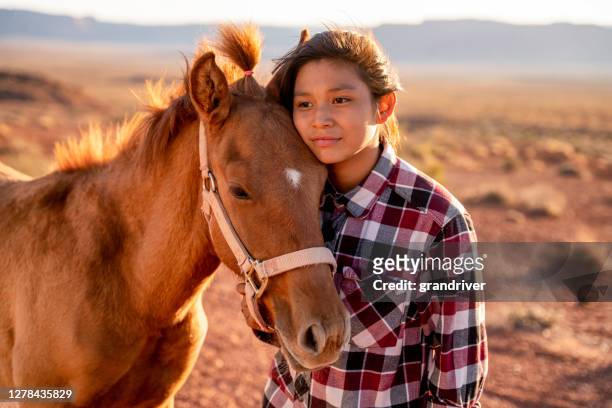 twaalf jaar oud navajo meisje liefdevol poseren met haar huisdier paard buiten in de buurt van het monument valley tribal park in noord-arizona in de schemering - american indian girls stockfoto's en -beelden