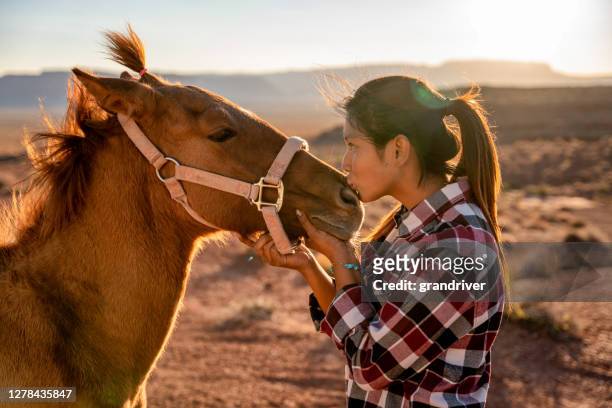 twelve year old navajo girl lovingly posing with her pet horse outside near the monument valley tribal park in northern arizona at dusk - horseback riding arizona stock pictures, royalty-free photos & images