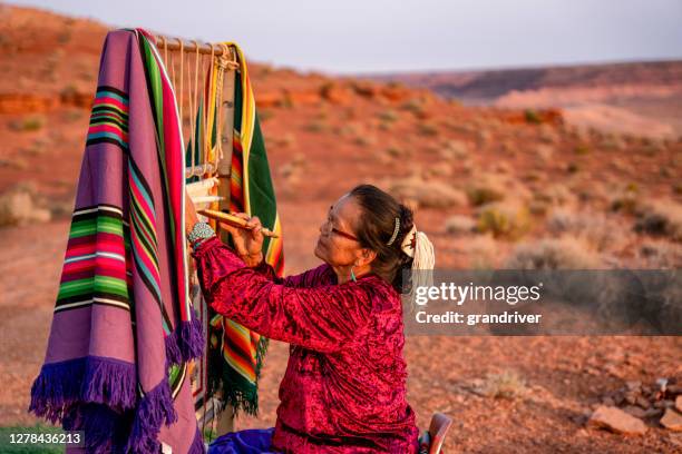 anciana mujer navajo tejiendo una manta tradicional o alfombra en un telar nativo americano auténtico en el desierto al atardecer cerca del parque tribal monument valley en el norte de arizona - tradicional fotografías e imágenes de stock