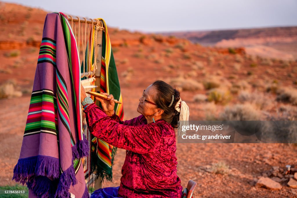 Elderly Navajo Woman Weaving a Traditional Blanket or Rug on an Authentic Native American Loom in the Desert at Dusk near the Monument Valley Tribal Park in Northern Arizona
