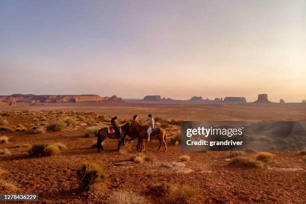 three teenage navajo people, one boy and two girls riding horseback through the desert near monument valley tribal park in northern arizona at sunset - northern arizona v arizona stock pictures, royalty-free photos & images