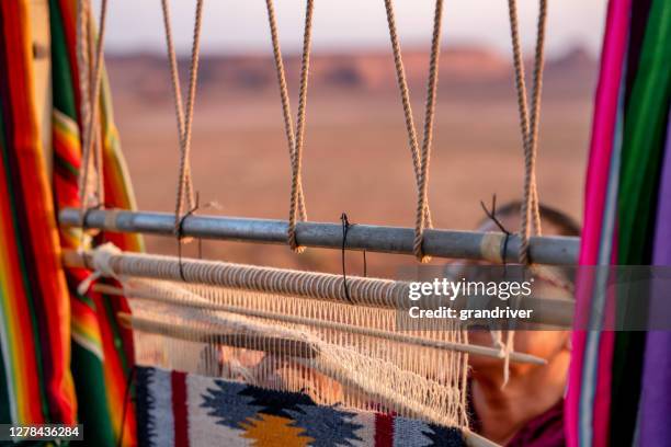 elderly navajo woman weaving a traditional blanket or rug on an authentic native american loom in the desert at dusk near the monument valley tribal park in northern arizona - wall hanging stock pictures, royalty-free photos & images