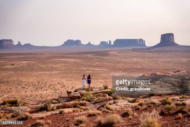 duas meninas adolescentes navajo nativas americanas olhando sobre o vasto deserto no norte do arizona monument valley tribal park navajo reserve - etnia cheroqui - fotografias e filmes do acervo