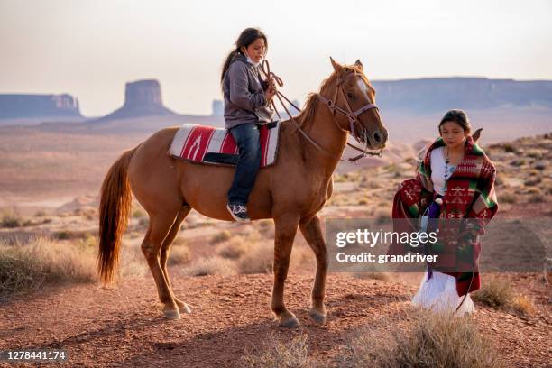 navajo kinderen, broer en zuster, jongen die paard bareback met meisje berijdt dat langs kant in de enorme woestijn in de reserve van navajo en het stammenpark van de vallei van het monument in noordelijk arizona loopt - cherokee indian women stockfoto's en -beelden