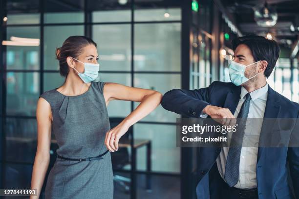couple of business persons greeting with an elbow bump - business relationship stock pictures, royalty-free photos & images