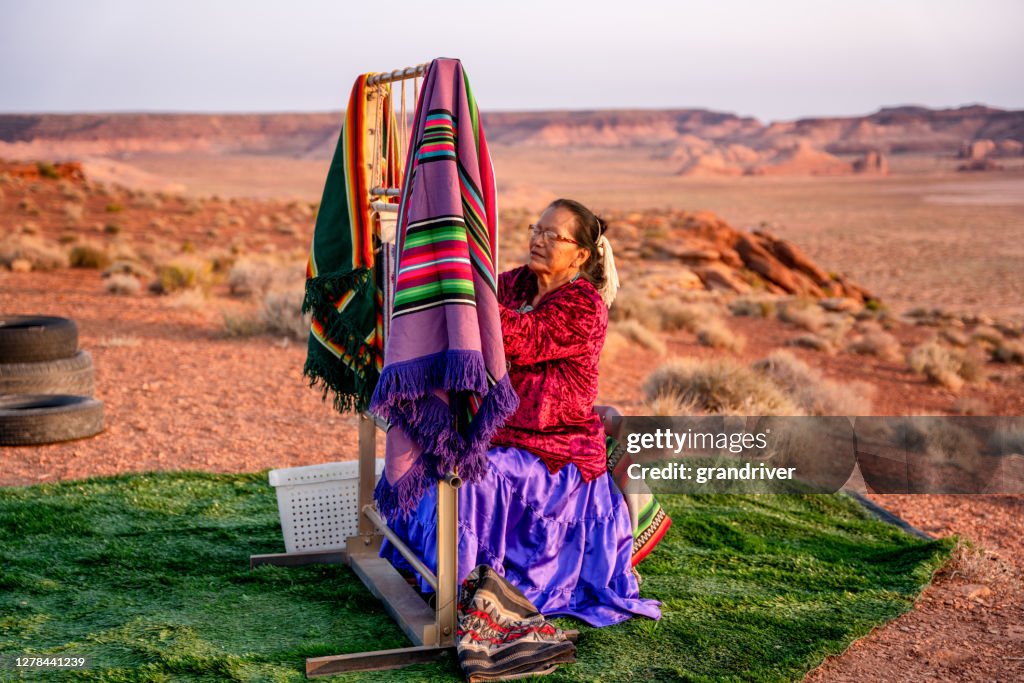Elderly Navajo Woman Weaving a Traditional Blanket or Rug on an Authentic Native American Loom in the Desert at Dusk near the Monument Valley Tribal Park in Northern Arizona
