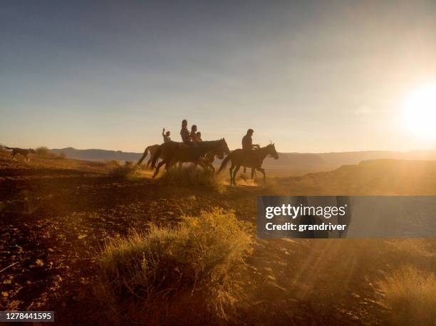 groep jonge navajo siblings die hun paarden bareback door de enorme woestijn in noordelijk arizona dichtbij het stammenpark van de vallei van het monument op het indische reserve navajo in de schemering berijden - apache stockfoto's en -beelden