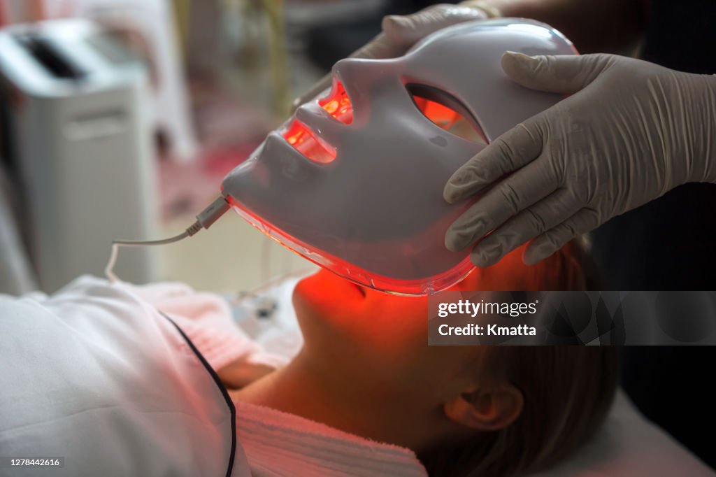 Woman getting LED mask regenerative treatment at the facial spa.