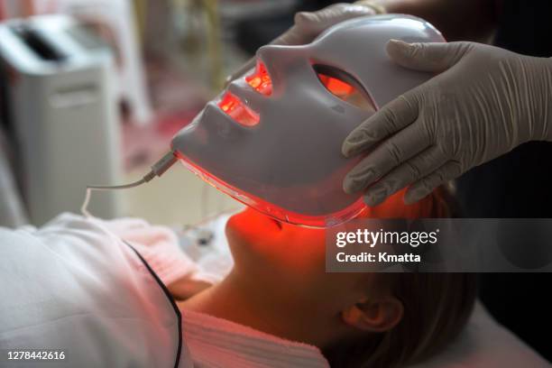 woman getting led mask regenerative treatment at the facial spa. - led stockfoto's en -beelden