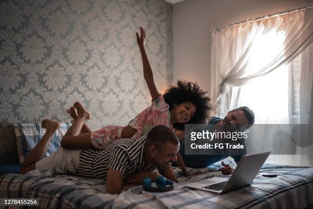 feliz familia en la cama usando el ordenador portátil - lovers 2020 film fotografías e imágenes de stock
