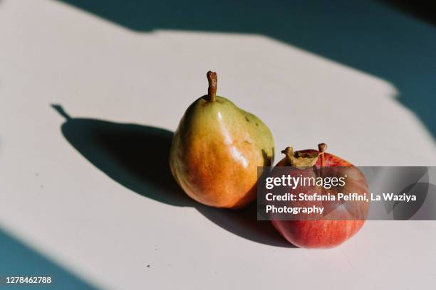 pear and apple casting a shadow on a white surface - studio shot of green apple stock pictures, royalty-free photos & images