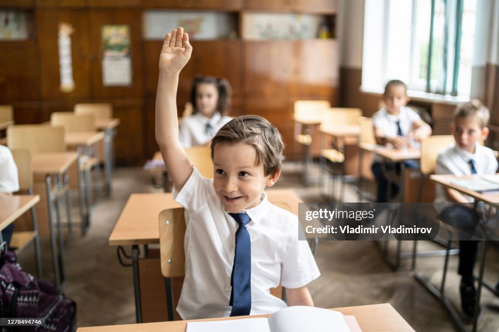 Schooljongen die hand in klasse op heft