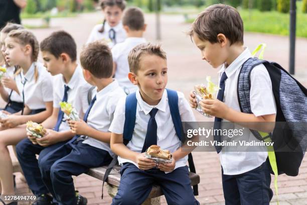 junge schüler essen nach der schule im park. - girls laughing eating sandwich stock-fotos und bilder