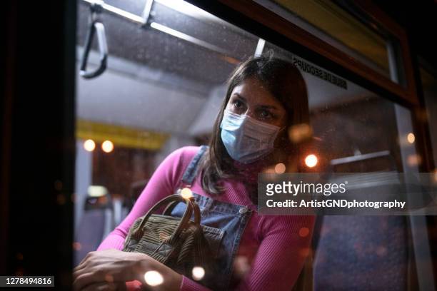 junge frau ist reisen mit den bussen in der nacht zeit und tragen gesicht maske - going home night stock-fotos und bilder
