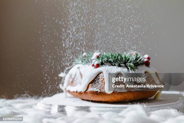 traditional christmas lemon bundt cake decorated with spruce branch and cranberrys. - tulbandcake stockfoto's en -beelden