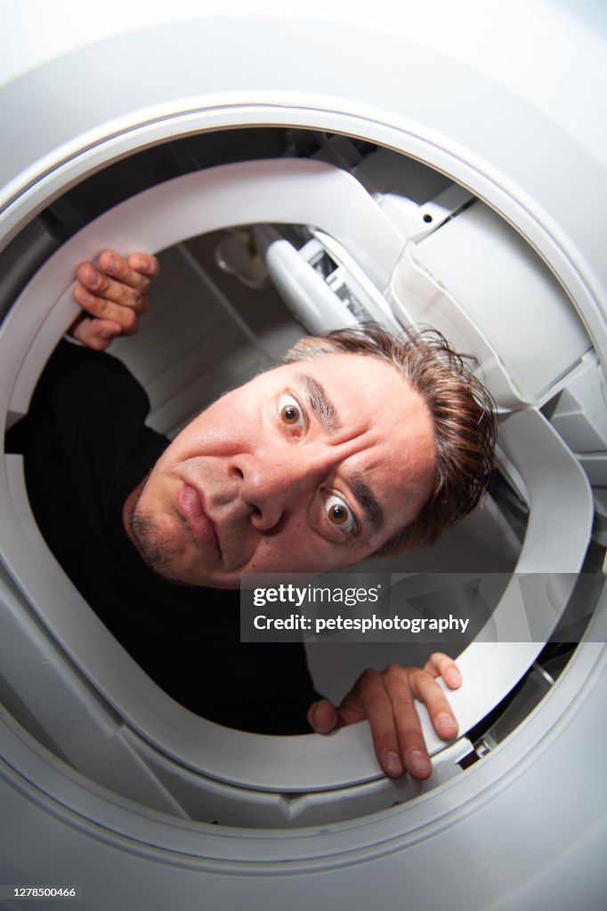 Man sticking his head down into a washing machine