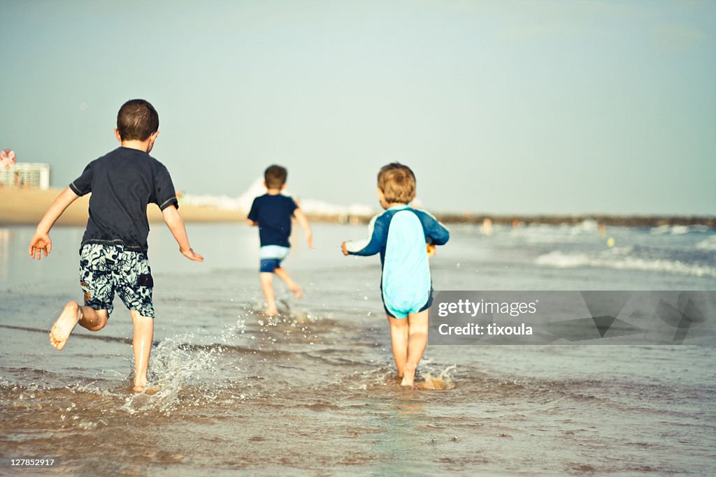 Boys running on beach shore