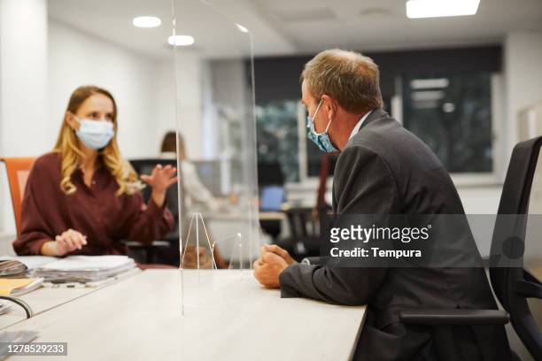 two colleagues meet behind a partition screen. - employee engagement mask stock pictures, royalty-free photos & images
