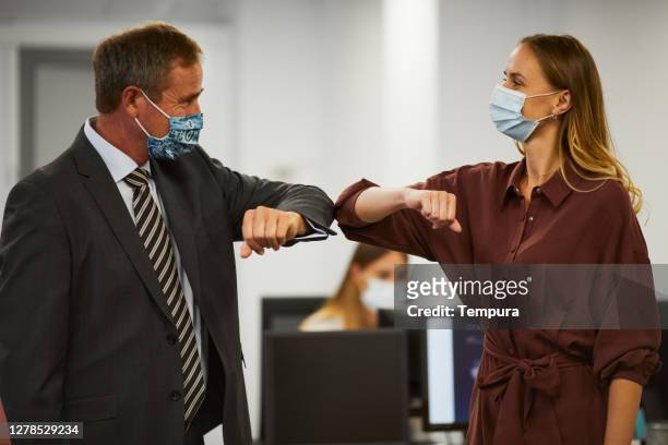 man and woman touching elbows and avoiding handshakes. - employee engagement mask stock pictures, royalty-free photos & images