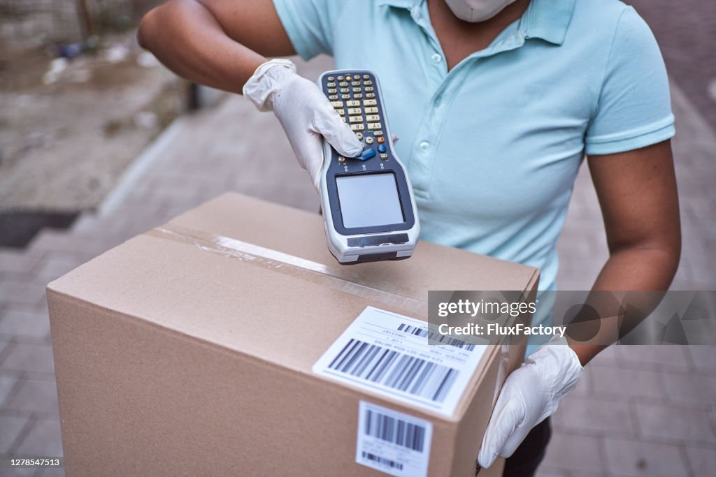 Delivery woman Black ethnicity scanning package barcode with bar code reader