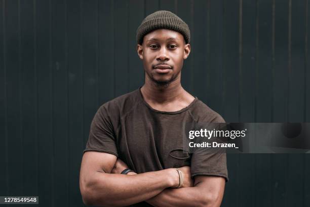 millennial african man looking at camera with arms crossed - black muscle men stock pictures, royalty-free photos & images