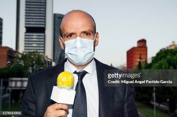 male journalist wearing mask with microphone standing on street in city - reportage portrait stock pictures, royalty-free photos & images