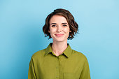 Photo portrait of cute smiling pretty girl with brunette short hair wearing green shirt isolated on blue color background