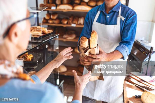 female customer receiving a parcel from bakery staff at counter - cacete imagens e fotografias de stock