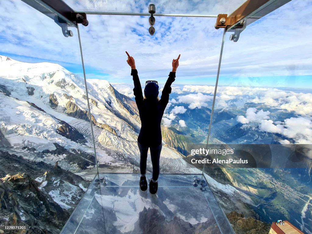 Frau bewundert den Blick aus dem Glaskasten, der Schritt in die Leere - Aiguille du Midi Skywalk