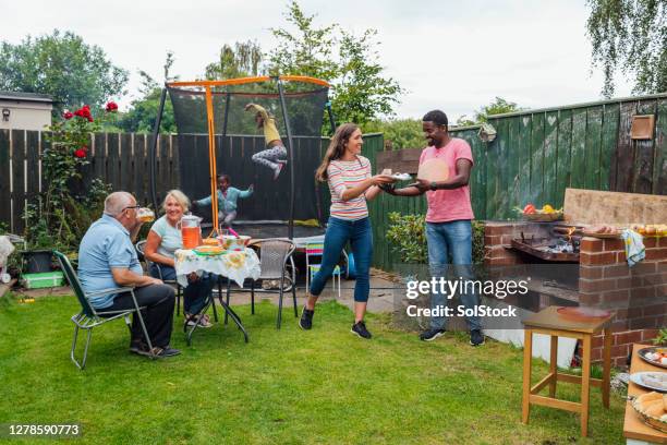 family making the most of summer - family barbeque garden stock pictures, royalty-free photos & images