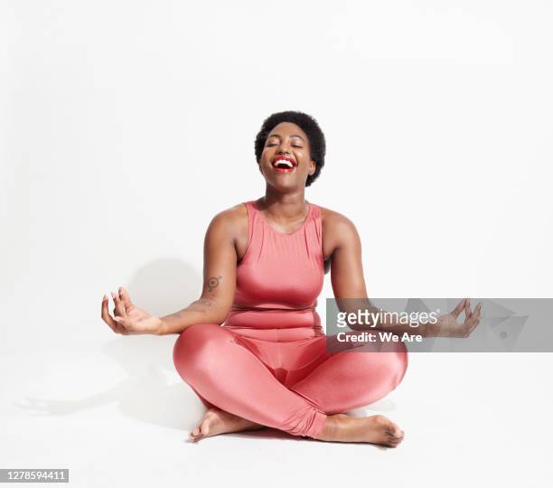 laughing woman in lotus position - yoga stock-fotos und bilder