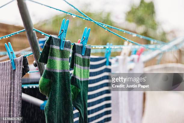 rain soaked laundry hanging on a clothesline in back garden - washing line stock pictures, royalty-free photos & images