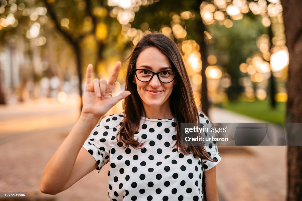 Mulher mostrando "Amor" na linguagem de sinais
