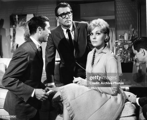 Howard Duff looking up, Kim Novak sits with Tony Randall sitting behind her in a scene from the film 'Boys' Night Out', 1962.