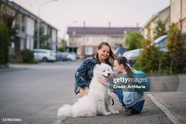 little schoolgirl happy to see her dog before or after school - dog greeting stock pictures, royalty-free photos & images