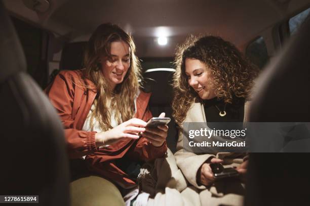 zwei frauen mit smartphones auf den rücksitzen eines autos - auto display stock-fotos und bilder