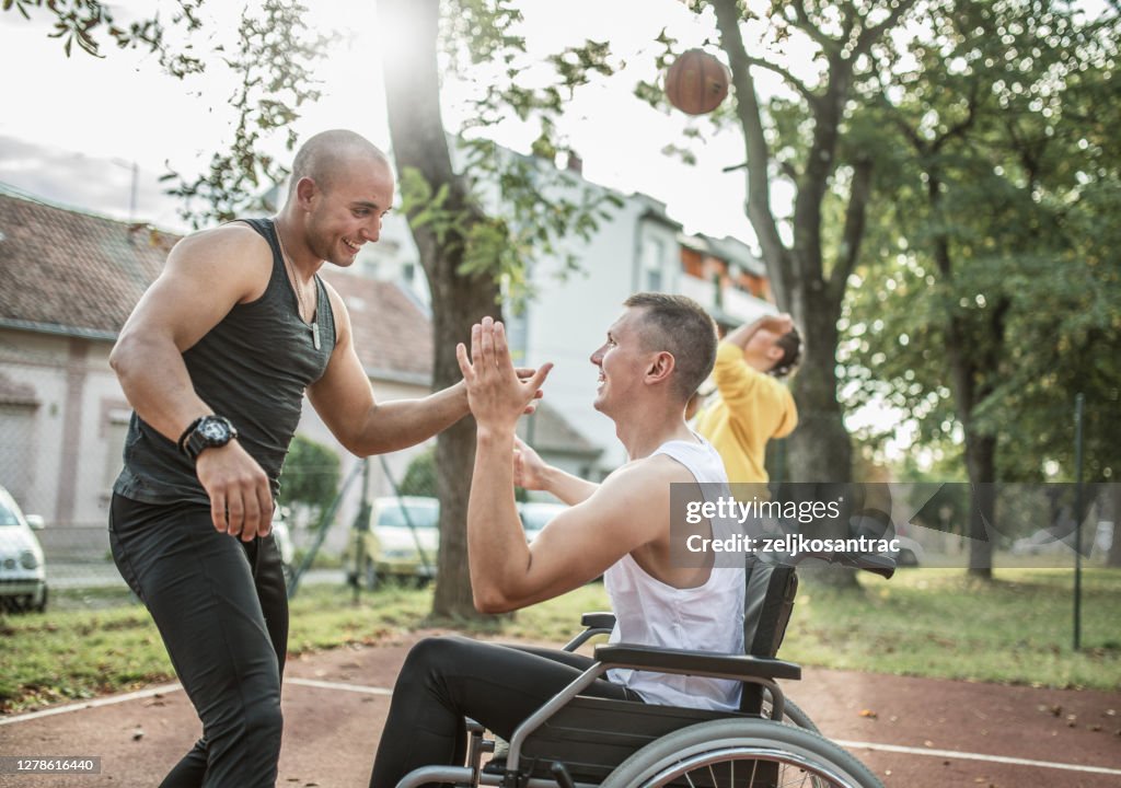 Behinderte Männer spielen Basketball mit Freunden