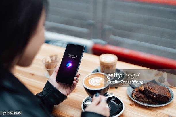 young woman using smart assistance on smart phone at cafe - alexa stock pictures, royalty-free photos & images