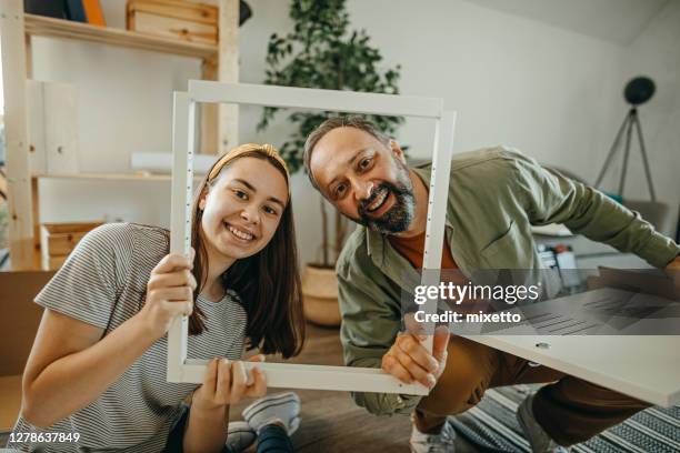 teenage girl and father looking through a picture frame - father daughter picture frames stock pictures, royalty-free photos & images