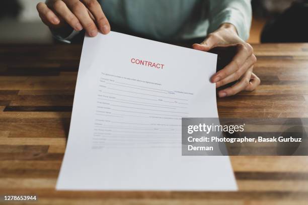 cropped hand holding a contract at desk - deal england stock-fotos und bilder