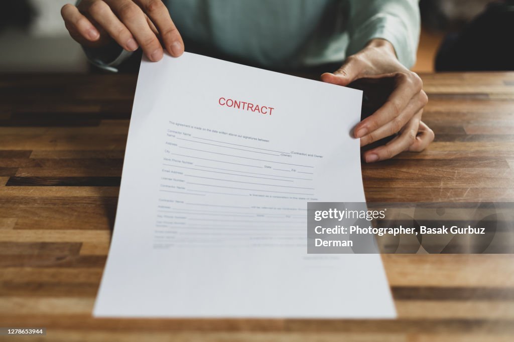 Cropped Hand Holding A Contract At Desk